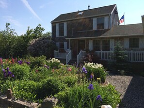 A two-story house with a white porch and a flag.