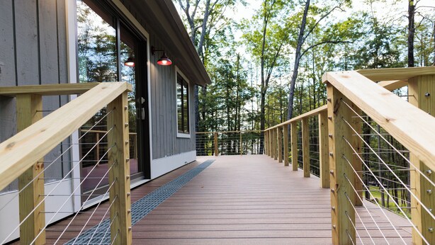 A wooden deck with railings leading to a building with large windows. - The Real Vermont All Seasons Get-Away Home - Part of Queche Lakes Country Club (Quechee)