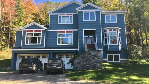 Ein zweistöckiges Haus mit Garage, Steintreppe und Auffahrt.