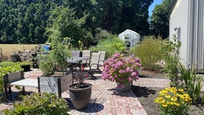 Une terrasse avec des meubles d’extérieur, des plantes en pot et un chemin de jardin.