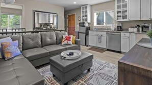 Un salon moderne avec un canapé gris, une table basse et un tapis à motifs.