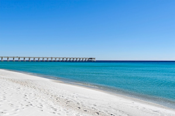 A beach with a pier extending into the ocean.