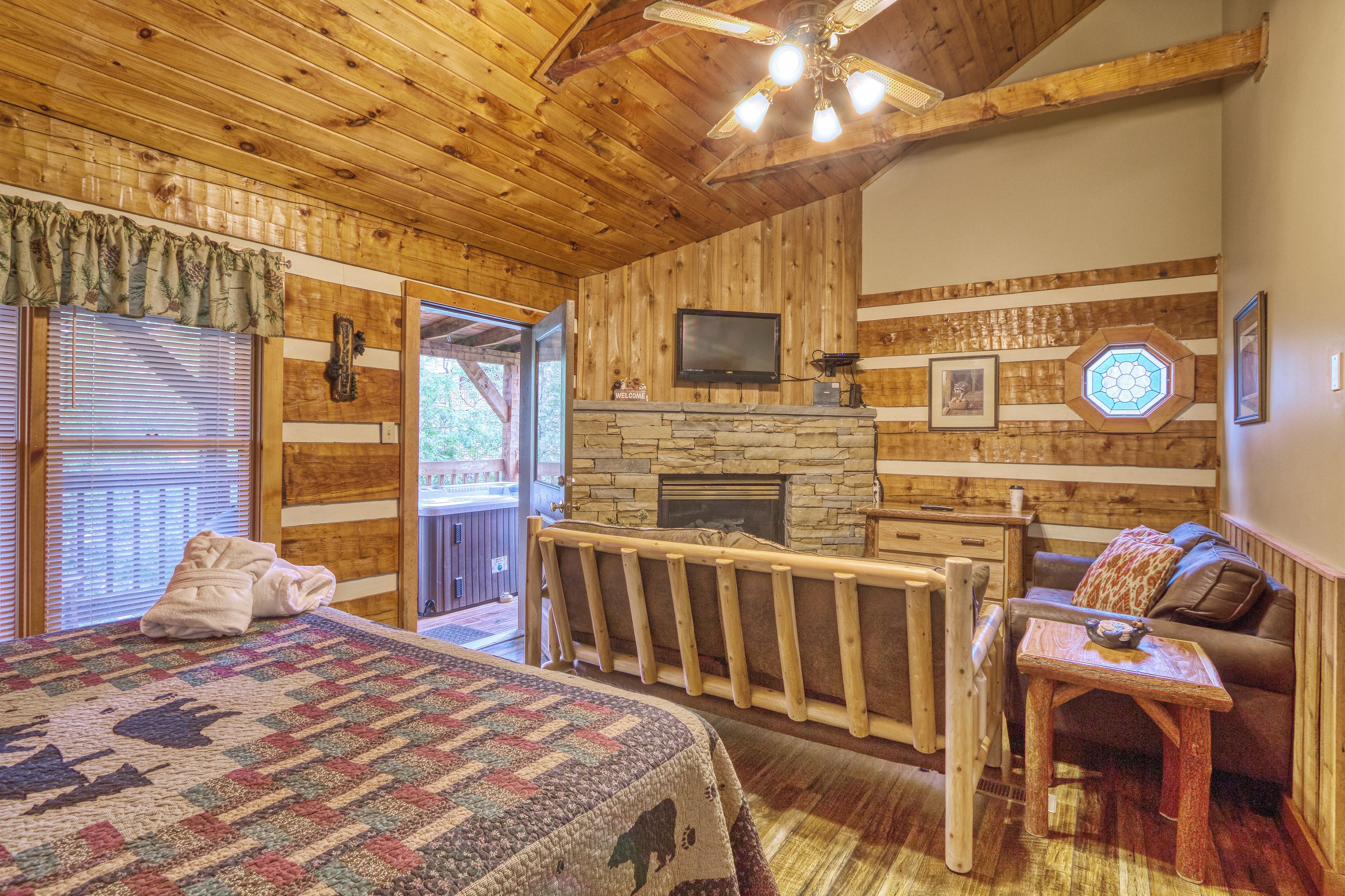 Ein gemütliches Zimmer mit einem großen Bett, einem Kamin aus Stein, einem Fernseher und einer Holzbalkendecke.