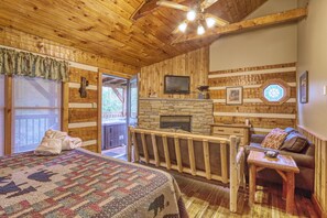 Una habitación acogedora con una cama grande, una chimenea de piedra, un televisor y un techo de madera.