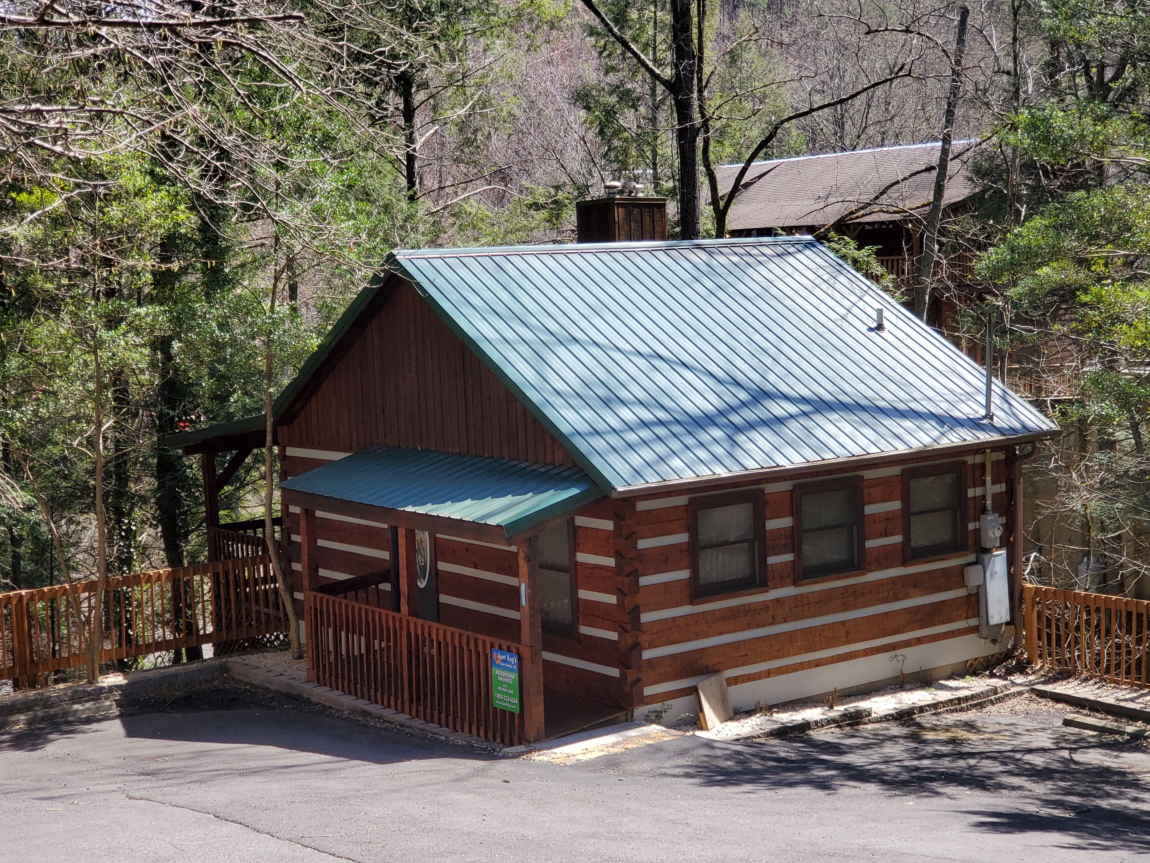 A small wooden cabin with a metal roof, surrounded by trees.