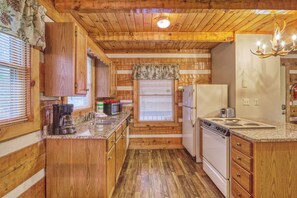 Une cuisine de style rustique, avec des murs en bois, un plan de travail en granit, des armoires en bois, une cuisinière et un réfrigérateur.