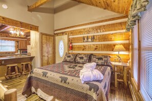 Ein gemütlicher Holzraum mit Bett, einem kleinen Tisch mit Lampe und einem Fenster mit Jalousien.