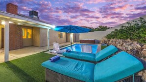 Um quintal com piscina, espreguiçadeiras e um espaço coberto com varanda.