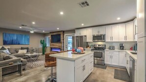 A modern kitchen with white cabinets, stainless steel appliances, and a central island. - Las Vegas Retreat- Private Pool, Game Room & Spa (Las Vegas)