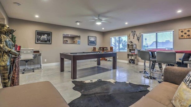 A spacious living room with a pool table, a leather couch, and a ceiling fan. - Las Vegas Retreat- Private Pool, Game Room & Spa (Las Vegas)