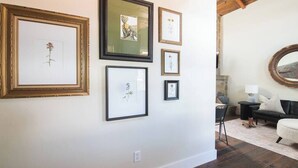 Quarto com parede branca, piso de madeira e sofá de couro preto.