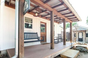 Eine überdachte Veranda mit einer Bank, Stühlen und einer Holzpergola.