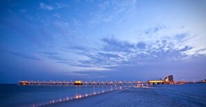 A pier extending into the water with lights along its length.