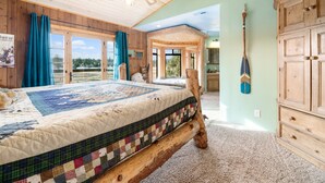 A bedroom with a large bed, wooden headboard, and a view of the outdoors. - Private Hot Tub! Game Room! Close to Slopes! Bright & open Amazing Views! (Big Bear City)