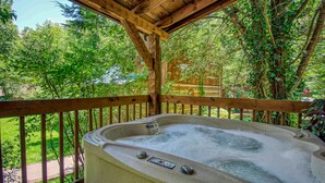 A hot tub under a wooden pergola with a view of a lush garden and a wooden fence. - Gatlinburg | Hot Tub | Pet Friendly | WiFi | Fireplace (GATLINBURG)