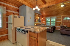 A log cabin interior with a kitchen, dining area, and living room.