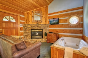 A wooden cabin interior with a stone fireplace, a wooden sofa, a wooden cabinet, and a large wooden-framed mirror.
