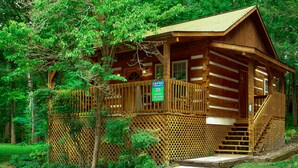 A wooden cabin with a wooden deck and stairs leading to the entrance. - Gatlinburg | Hot Tub | Pet Friendly | WiFi | Fireplace (GATLINBURG)
