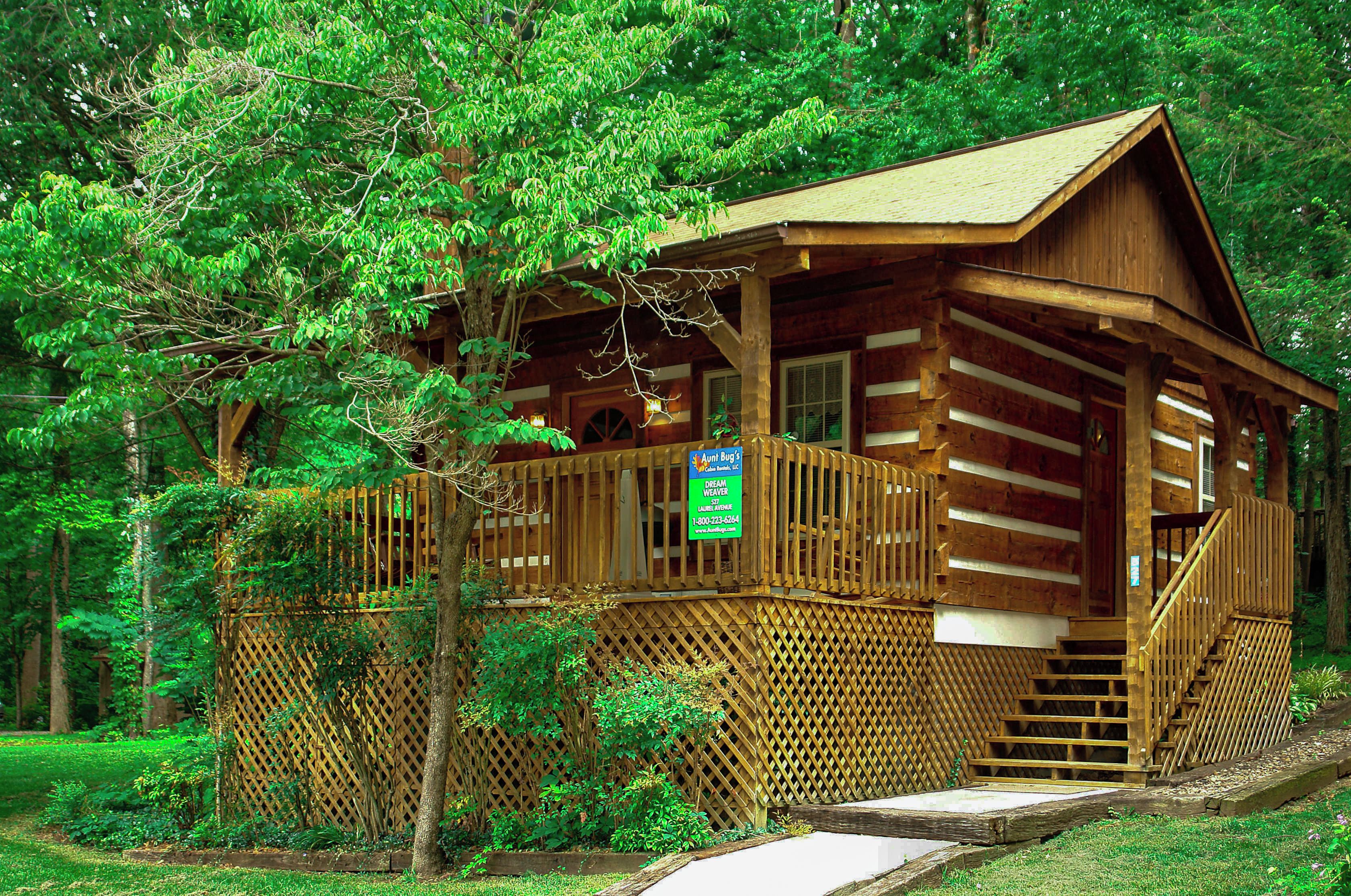 Une cabane en bois dotée d’une terrasse en bois et d’un escalier menant à l’entrée.