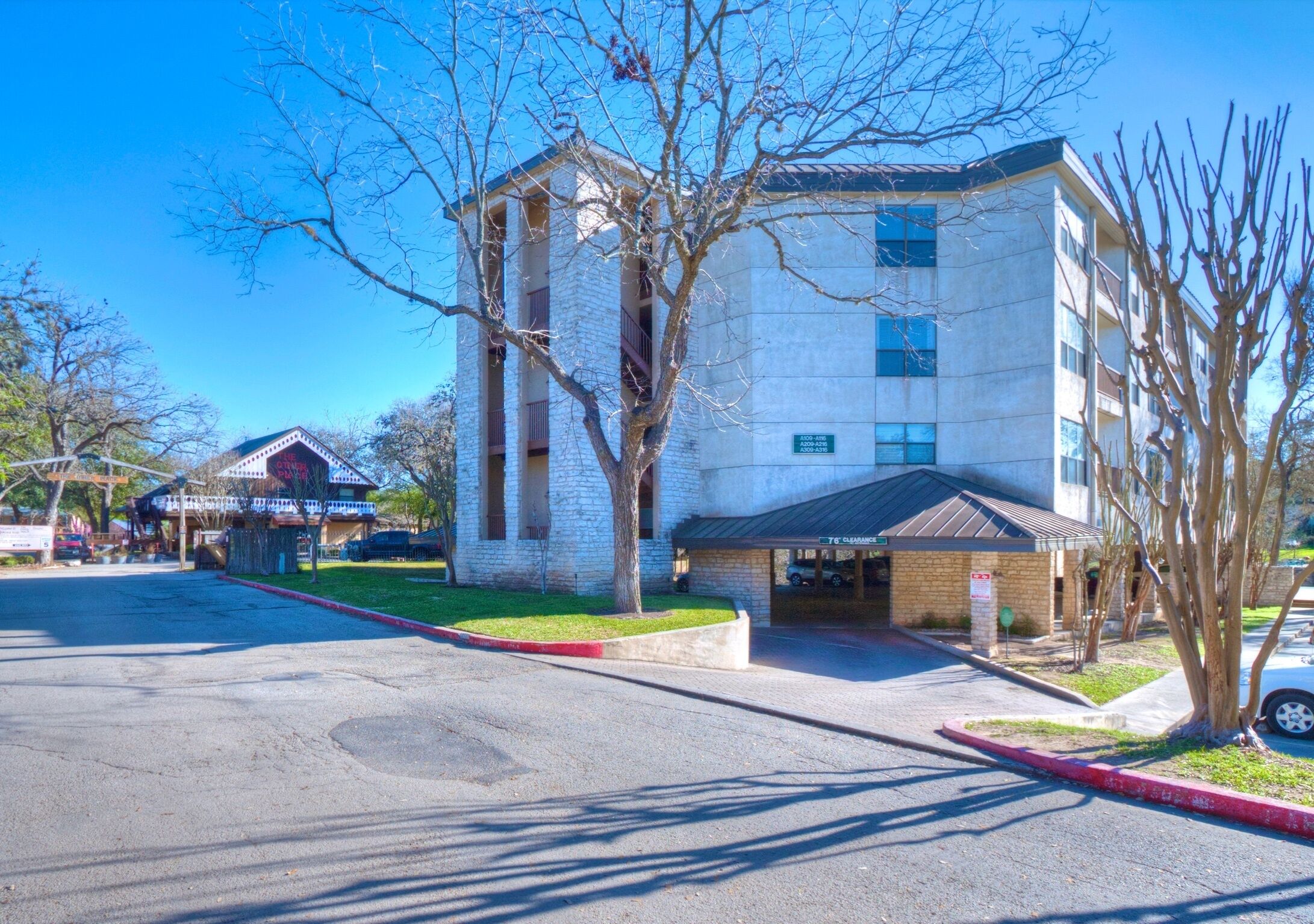 A multi-story building with a stone facade, a covered entrance, and a parking lot.