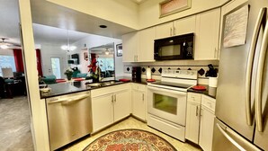 A kitchen with white cabinets, a stainless steel refrigerator, a microwave, a stove, and a dishwasher. - Updated Single Story Comal River Condo with Pool-Walk to Downtown NB (New Braunfels)