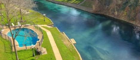 Un río con una poza azul y clara a la izquierda, rodeada de un área verde con un sendero.