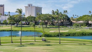 Een golfbaan met een waterpartij, palmbomen en gebouwen op de achtergrond.