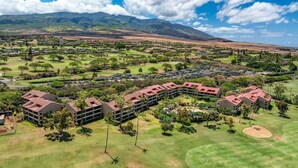 Een groot resort met meerdere gebouwen, uitgestrekte groene gazons en een bergachtige achtergrond.