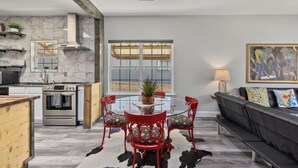 A modern kitchen with a built-in oven and a dining area with a glass table and red chairs.