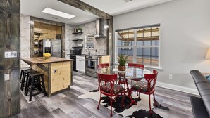 A modern kitchen with a central island, red chairs, and a cowhide rug.
