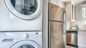 A compact laundry room with two front-loading washing machines and a stainless steel refrigerator. - City Escape Living (Burbank)