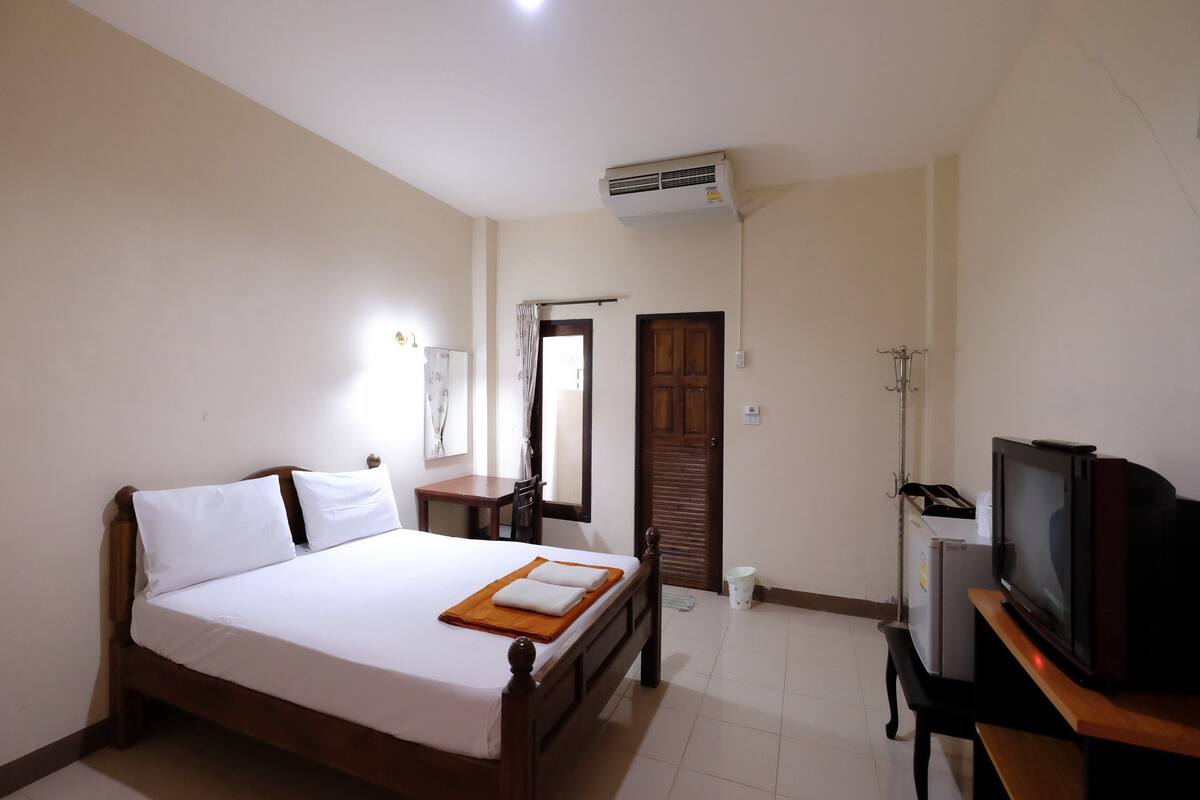 Una habitación de hotel con cama, televisión, escritorio y armario.