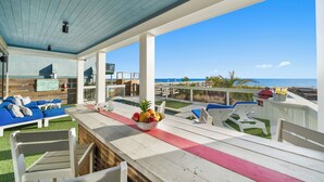 A covered outdoor area with a pool, lounge chairs, and a view of the ocean.