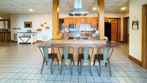 A spacious kitchen with a central island, wooden cabinets, and a modern stove.