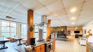 A spacious kitchen with a stone fireplace, wooden cabinets, and a large island.