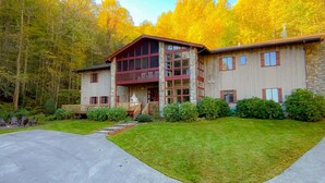 A two-story lodge with a stone facade, a balcony, and a stone chimney.
