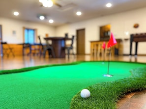 Un parcours de minigolf avec un gazon vert, une balle de golf blanche et un drapeau rouge.