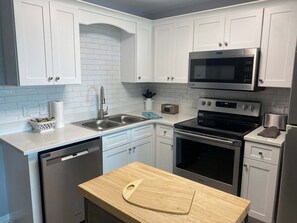 A modern kitchen with white cabinets, a stainless steel microwave, a stove, and a dishwasher. - Gulf Shores Plantation Resort 4307 (Gulf Shores)