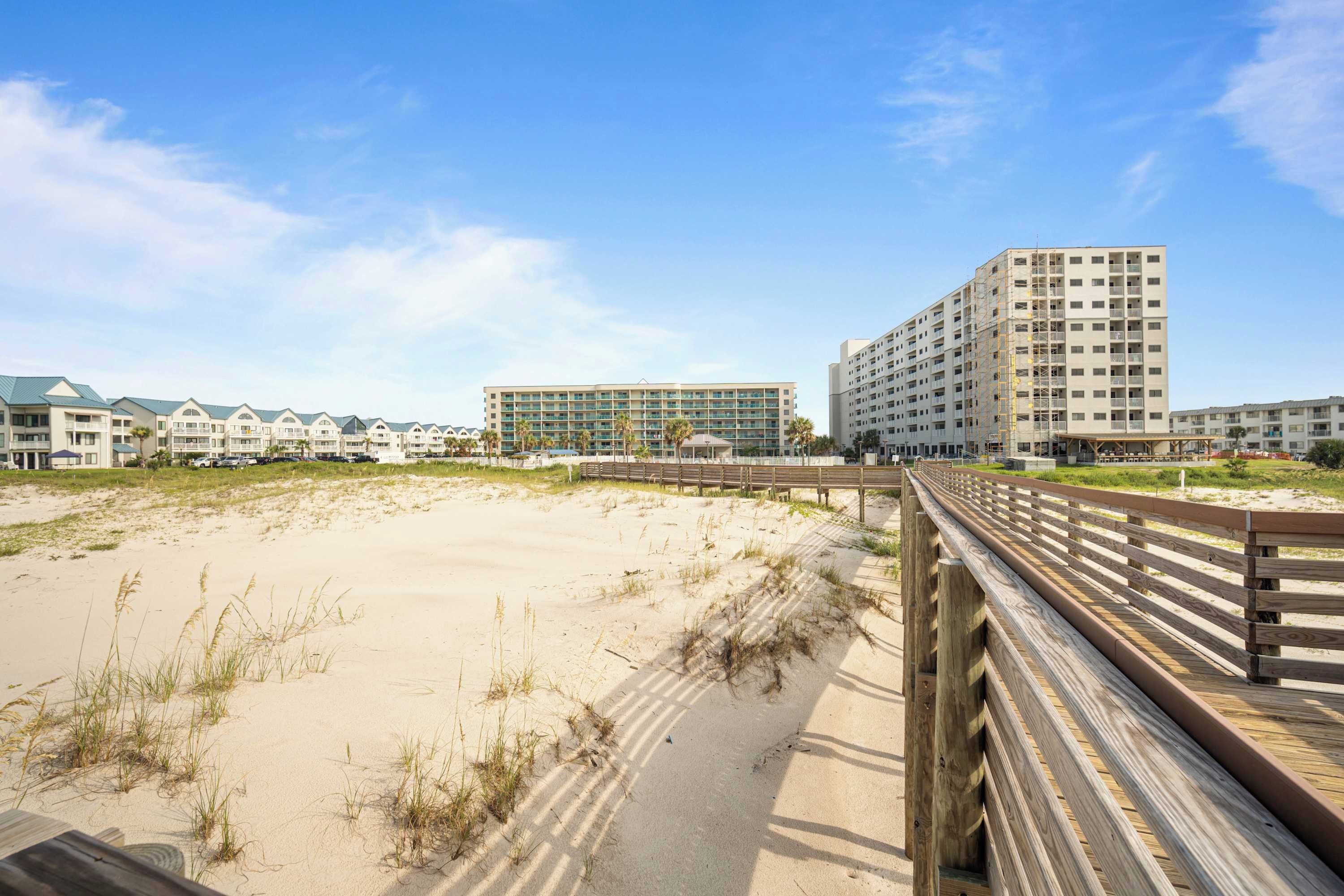 A beachfront hotel with multiple buildings, a wooden boardwalk, and sandy beach.