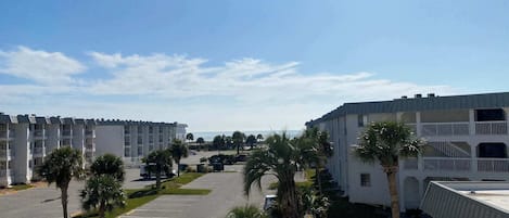 A view of a hotel with multiple buildings, a parking lot, and palm trees.