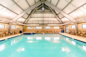 An indoor swimming pool with a high ceiling, multiple windows, and lounge chairs along the sides. - Gulf Shores Plantation Resort 4307 (Gulf Shores)