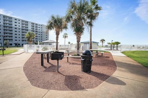 A park area with a barbecue grill, picnic tables, and a trash can. - Gulf Shores Plantation Resort 4307 (Gulf Shores)