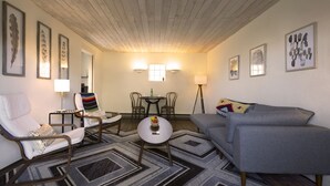 Una sala de estar con sofá, sillones, una mesa de centro y un comedor con sillas y una mesa.