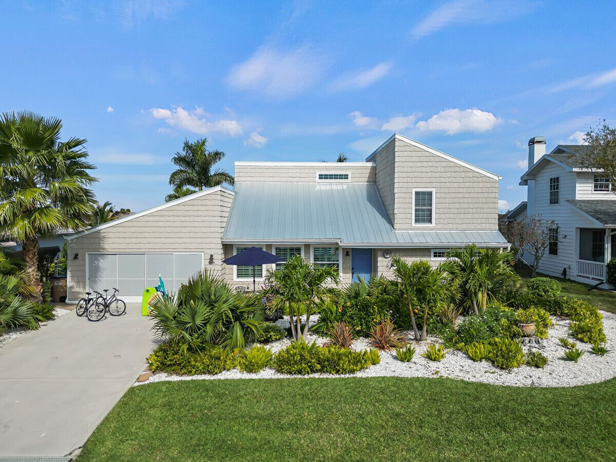 A single-story house with a garage, a front yard with various plants, and a bicycle parked outside.