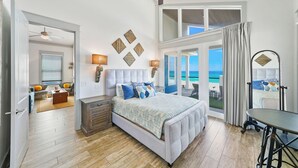 Een slaapkamer met een bed, een bureau en uitzicht op de oceaan.