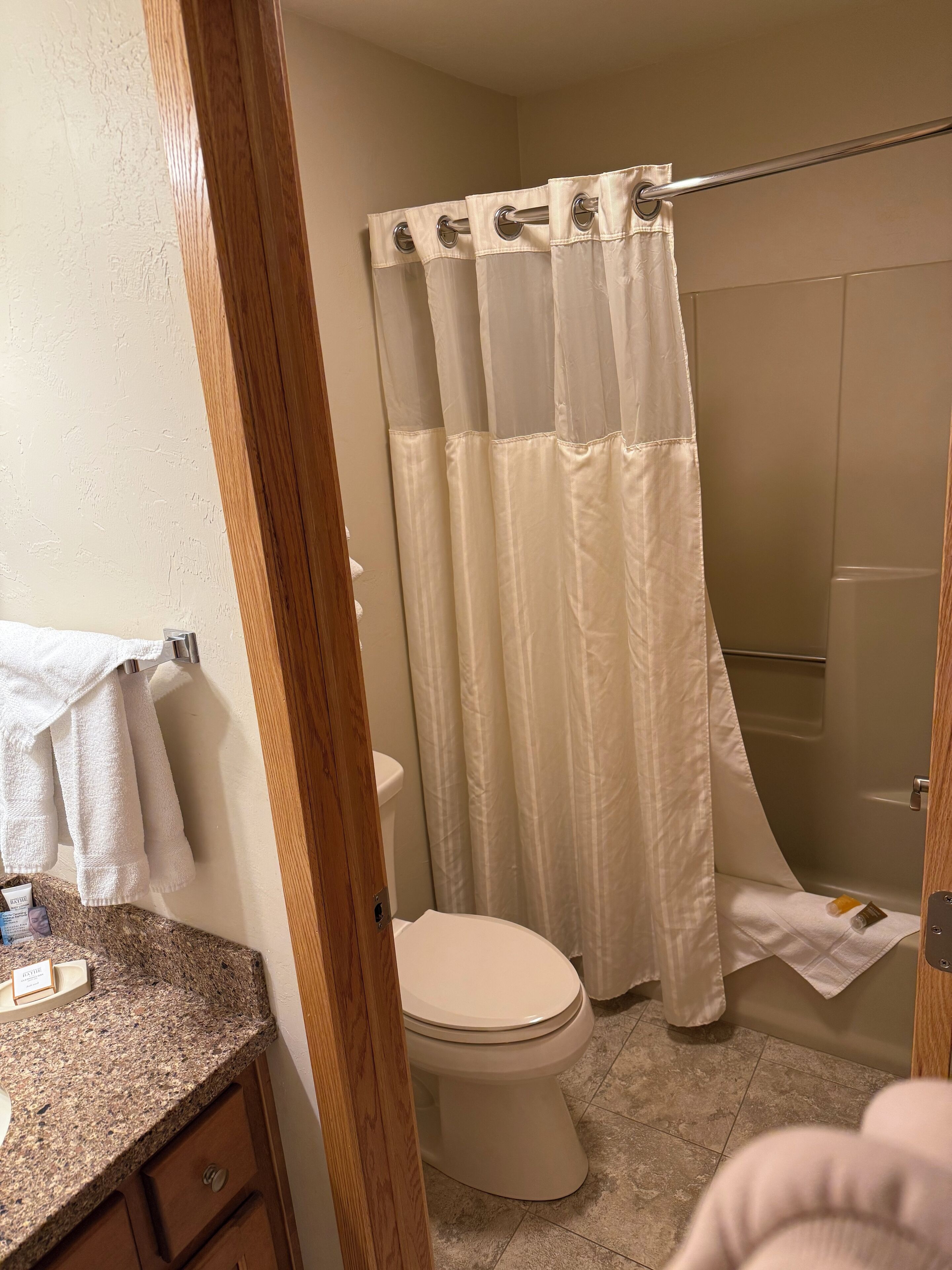 Une salle de bain équipée de toilettes, d’un rideau de douche et d’un porte-serviettes avec des serviettes.