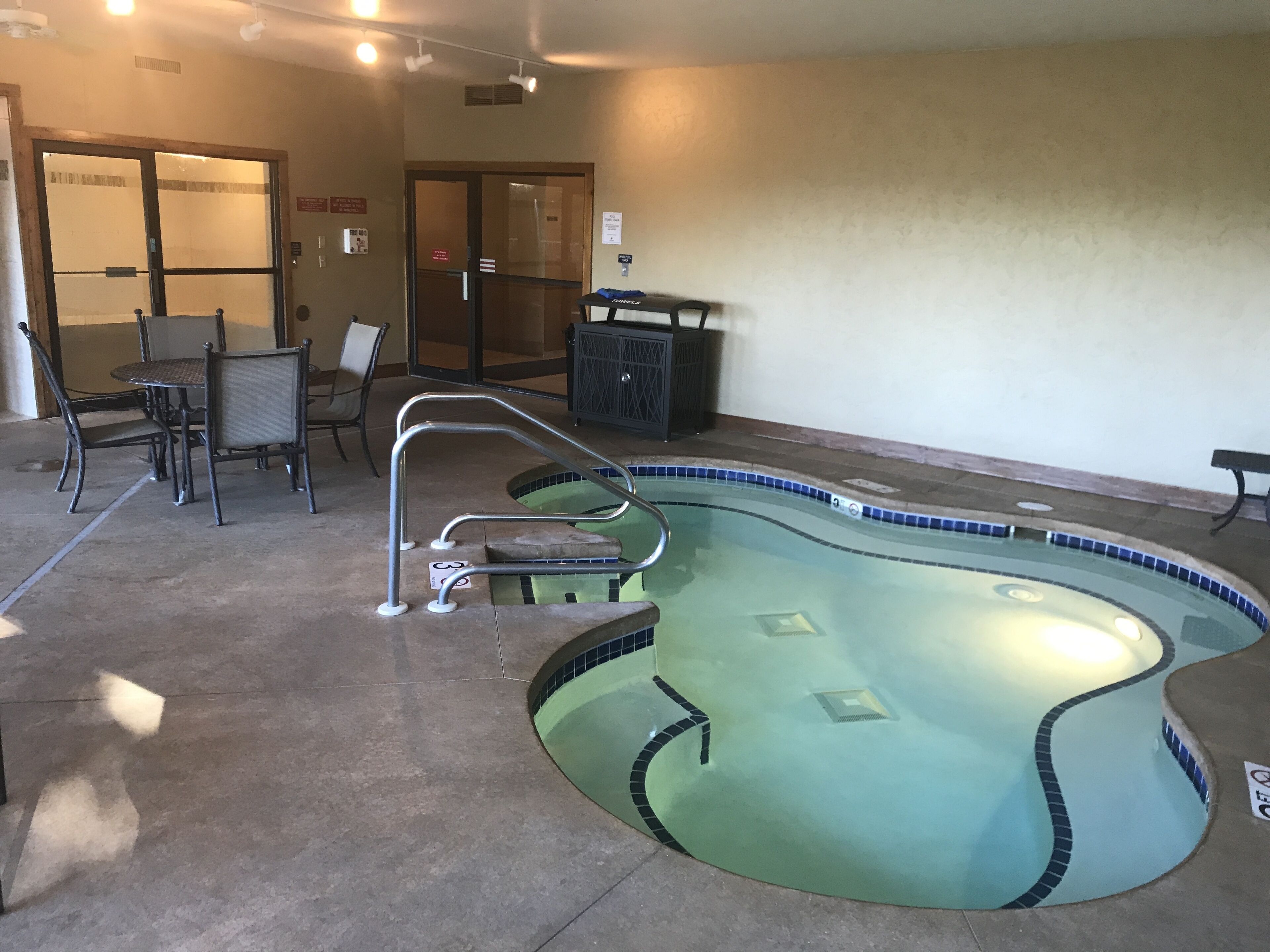 Ein Poolbereich mit Whirlpool, Stühlen und einem Tisch.