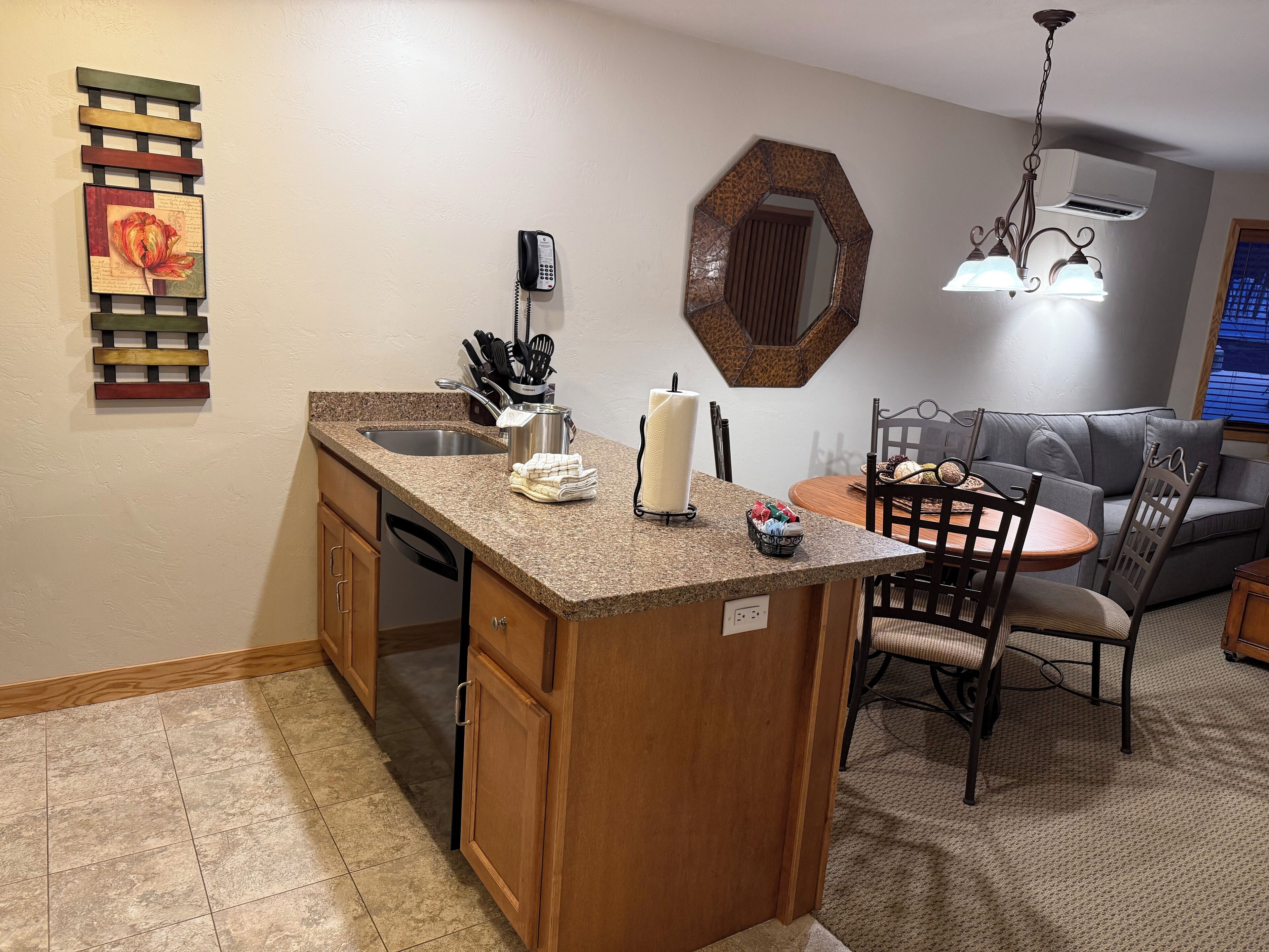 A kitchen with a granite countertop, a built-in dishwasher, and a dining area with a round table and chairs.