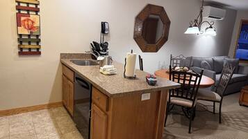 A kitchen with a granite countertop, a built-in dishwasher, and a dining area with a round table and chairs.