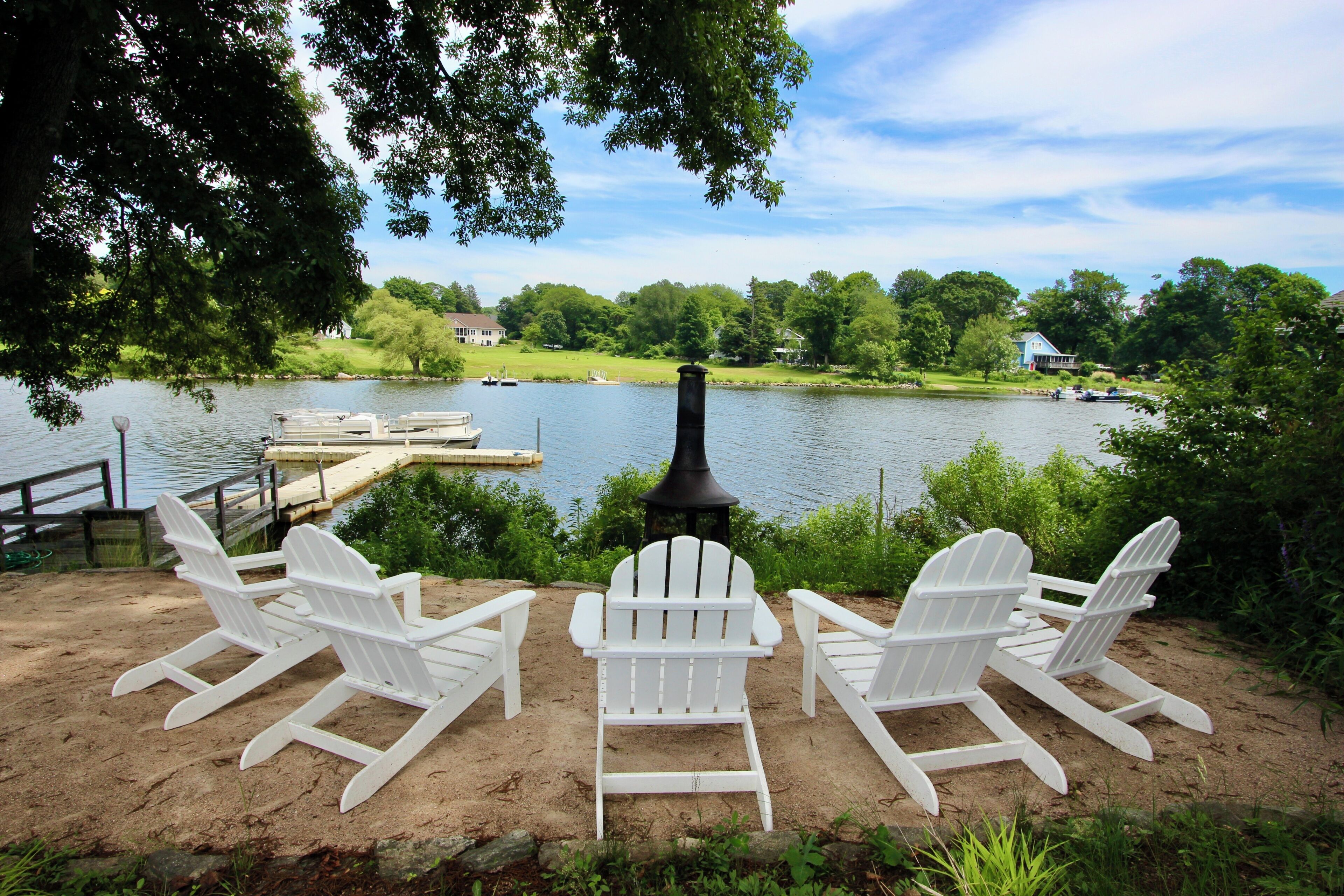 Une vue sur le lac, avec un quai, des chaises Adirondack blanches et une cheminée.